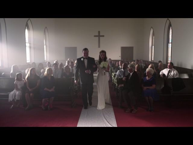 People turning to watch a father escort a bride down the aisle.