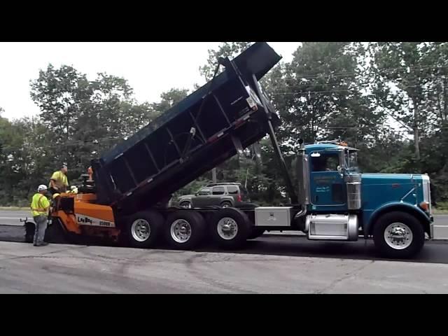 Paver pushing a truck as it dumps into the hopper