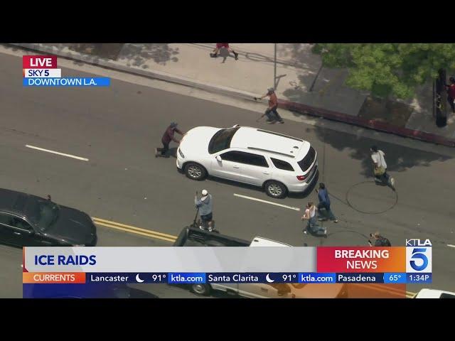 Protester tries to stop ICE SUV from leaving site of raid in L.A.