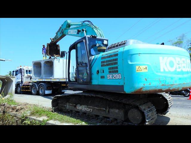 Kobelco Excavator Truck Unloading And Installing Precast Box On The Storm Drain Construction