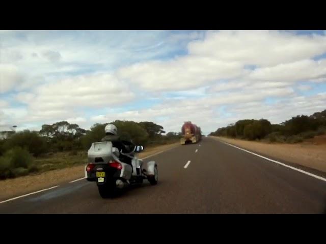 Road Train near Coober Pedy SA being passed by Triumph Rocket 3 towing a camper trailer.