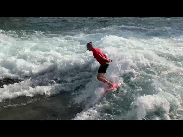 Surfer in roter Kleidung auf der Welle der Mühleschleuse