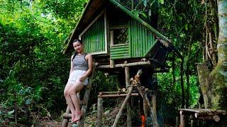 Girl builds survival shelter in wilderness area with rising flood waters , bushcraft & campfire fish