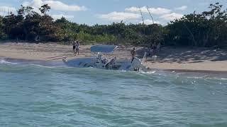 Salvaging boat on the beach with waves crashing over the side full of sand Pecks Lake Stuart Florida