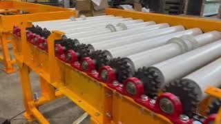 Chain-driven roller conveyor with a guide rail for cargo