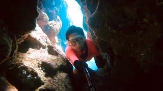 Freediving Girl Exploring a Coral Tunnel with Narrow Passage