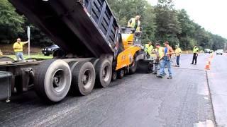 Dump truck feeding asphalt into the paver as the paver pushes the truck