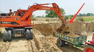 Excavator machine fills the Belarus Tractor trolley with the sand