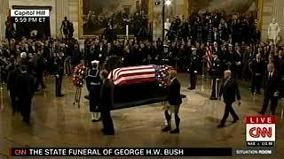 Who is the Man with the prosthetic legs wearing shorts, walking with a cane at H. W. Bush’s funeral?