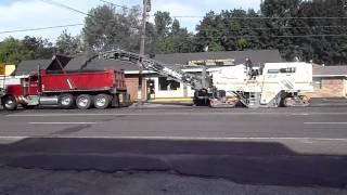 Over view of an asphalt mill cutting the road and loading a truck