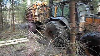 Valtra forestry tractor with big, fully loaded trailer logging in wet forest