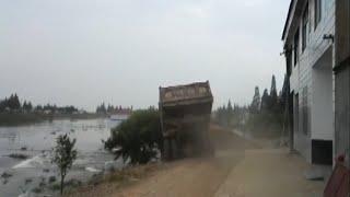 Trucks Carrying Rocks Driven into Flood to Block Dyke Breach in Hunan