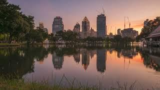 Bangkok skyline taken at sunset from Lumpini park - Timelapse night to day transition - 4k