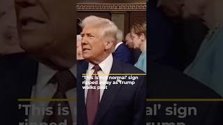 ‘This is not normal’ sign ripped away as Trump walks past