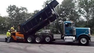 Paver pushing a truck as it dumps into the hopper