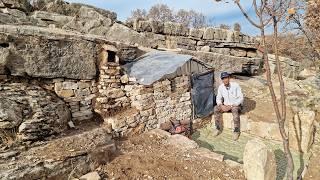 Building a survival shelter with a stone fireplace in the mountains for rain and snow