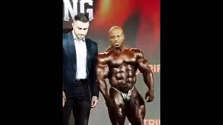 An absolute GIANT strongman Brian Shaw presenting bodybuilding trophies