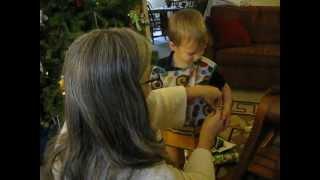 Mom helping toddler son open Christmas present