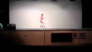 Kid solves Rubik's cube while unicycling and reciting periodic table of elements