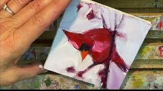 Painting a small red cardinal bird with oil.