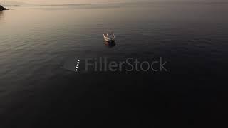 Aerial view of empty boat in quiet sea at sunset