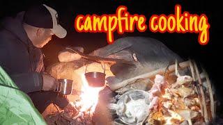 Wild camping in mountain forest.Cooking grilled chicken legs and meat over the campfire.