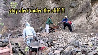 The manual sand miners sifting the black sand under the cliff must always be careful and alert