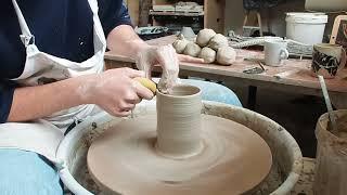 The worker uses a brush to draw patterns directly on the rustic background