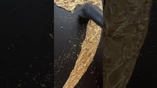 Cleaning the pieces of gold leaf from the canvas with a vacuum cleaner