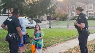 Two Overland Park police officers help out trick-or-treaters on Halloween