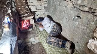 Building a warm and cozy shelter for survival in the rain between rocky cliffs in the mountains