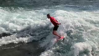 Surfer in roter Kleidung auf der Welle der Mühleschleuse